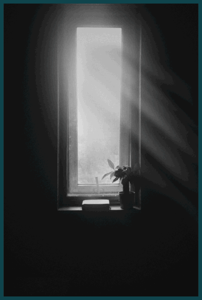 Black and white photo of a window with rays of light streaming inside (via Pexels).